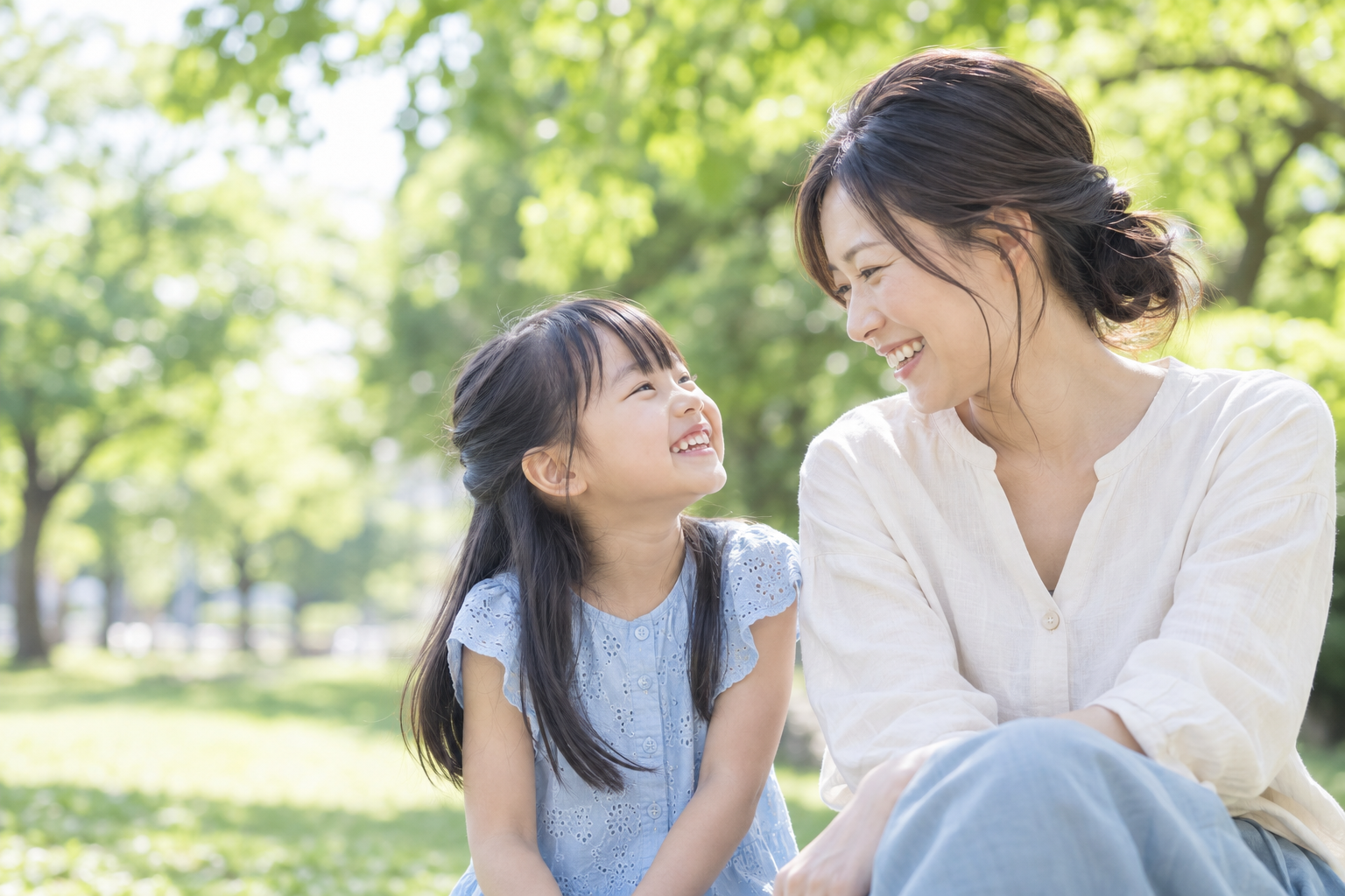 木漏れ日の中で笑顔を交わす親子のイメージ